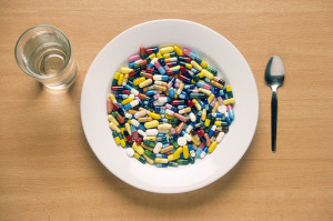 A plate filled with tablets, next to a glass of water and a spoon